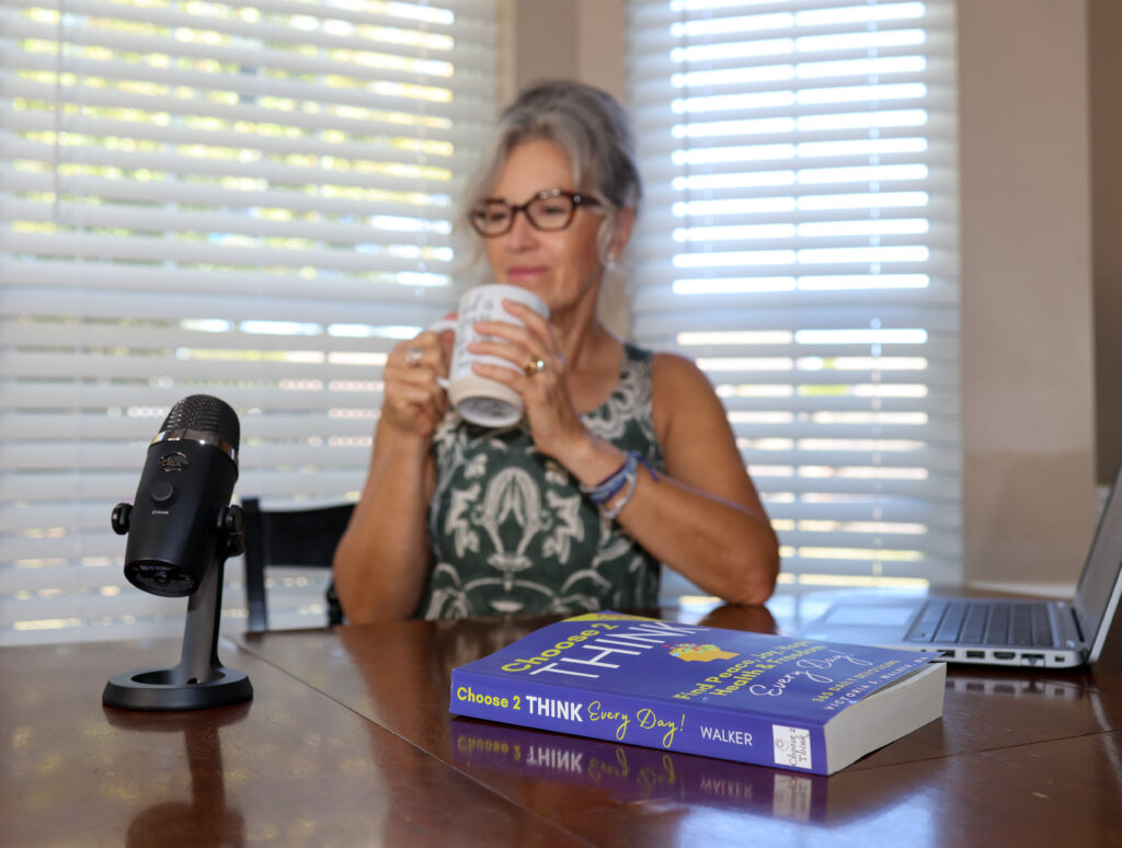 Victoria drinking coffee, with microphone and Choose 2 Think yearly devotional on table